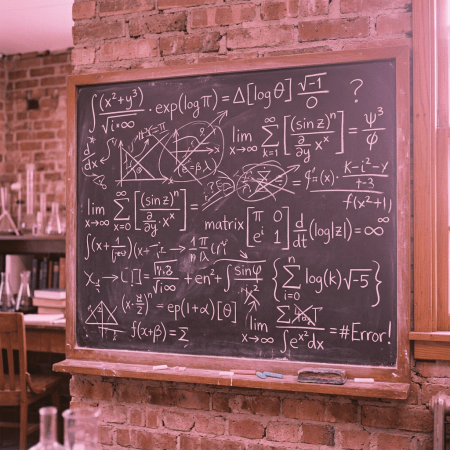 Chalkboard covered with mathematical equations, graphs, and formulas in a classroom